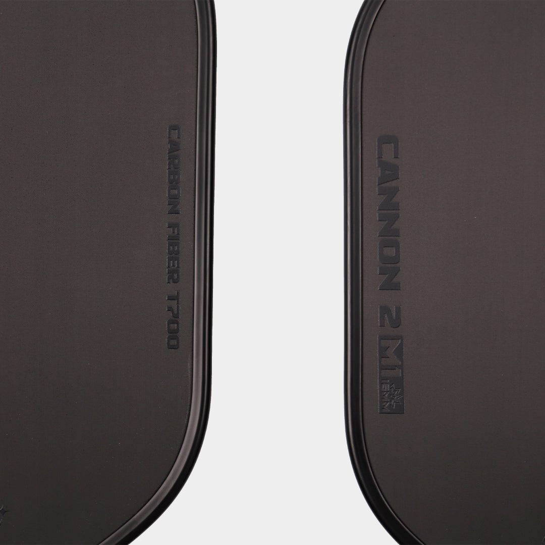 Close-up detail of a black pickleball paddle face featuring “CARBON FIBER T700” on one side and “CANNON 2 M1” on the other
