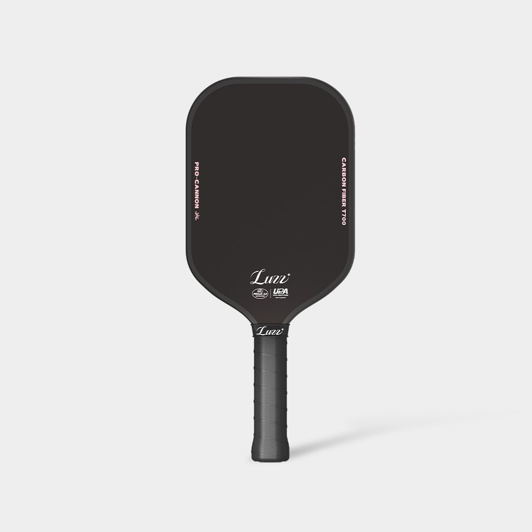 LUZZ Cat Paw Cannon pickleball paddle featuring a black paddle face with a light pink LUZZ logo and UPA-A and USAP certification logos at the bottom, light pink “PRO-CANNON” and “CARBON FIBER T700” lettering on each side, and a solid black handle