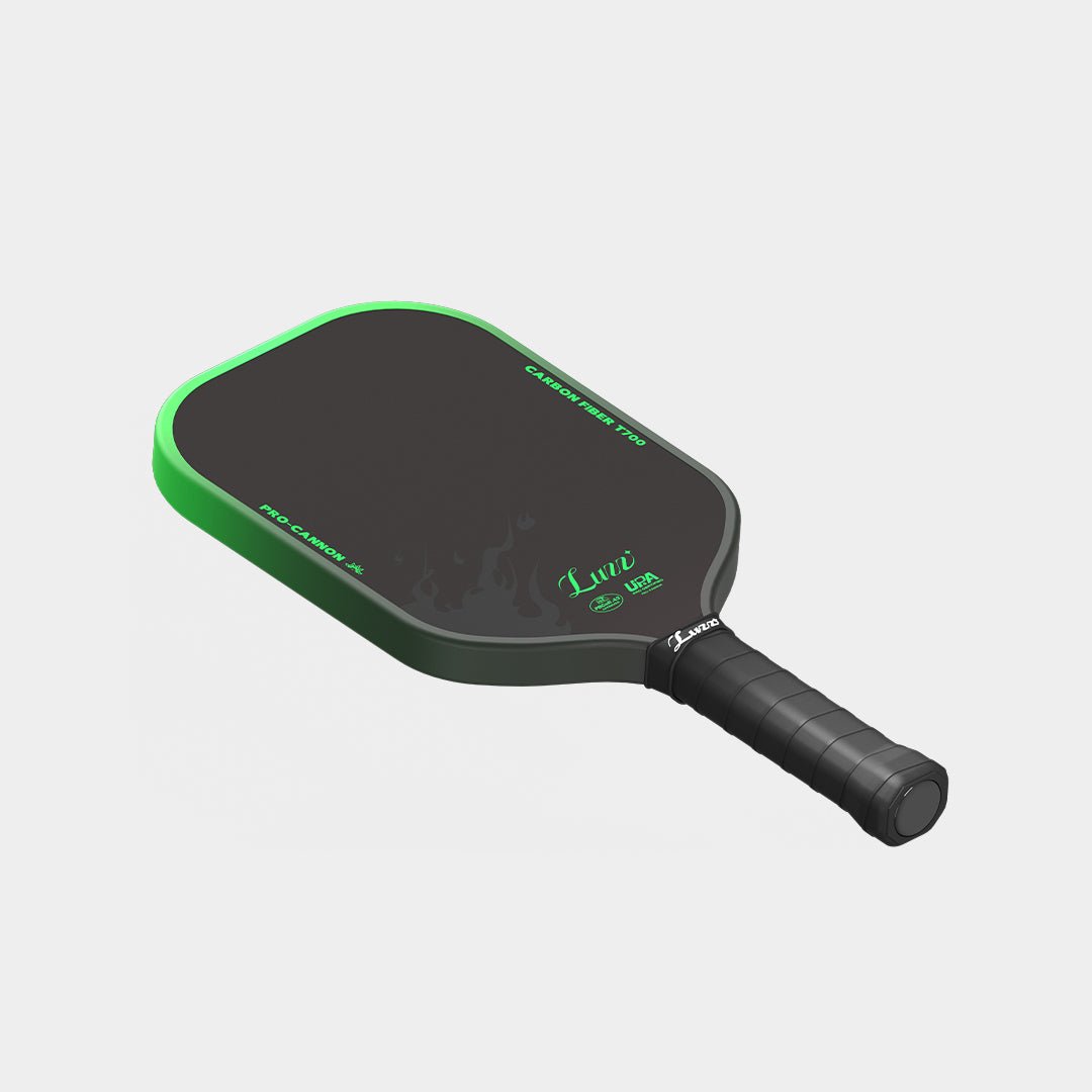 LUZZ Green Flame Cannon pickleball paddle angled flat-lay view featuring a green-to-black gradient side edge with black “TOXIC INCENDIARY” lettering and a black handle