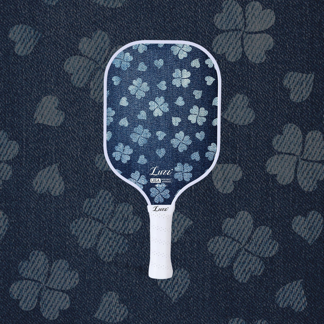 LUZZ Lucky Denim Original Paddle featuring a denim-blue paddle face with a four-leaf clover graphic, LUZZ logo at the bottom, and a white handle