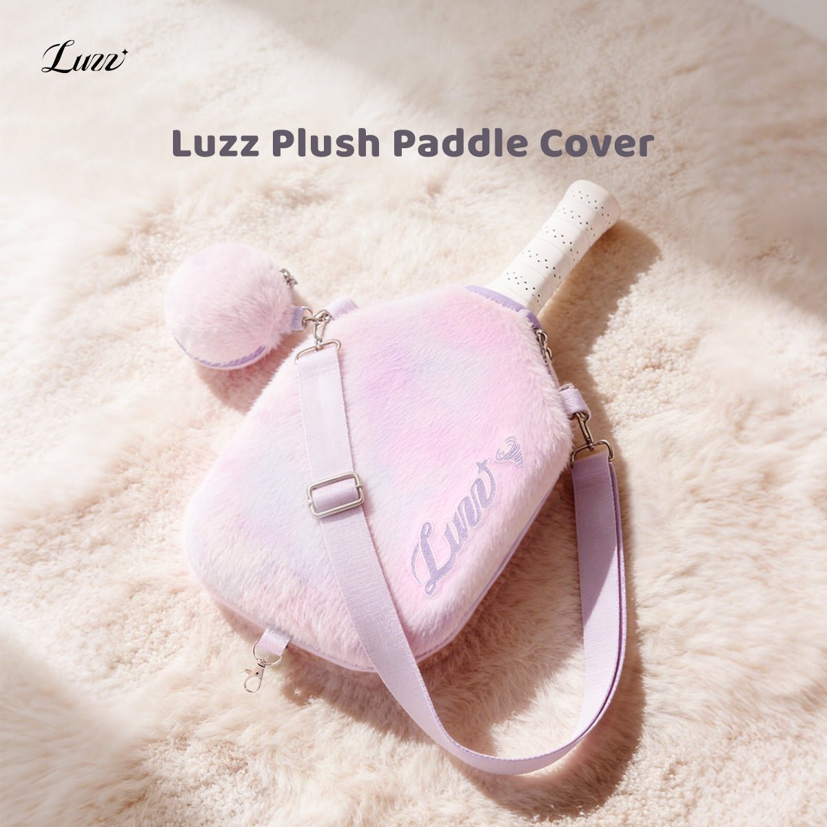 Pink-and-purple gradient plush pickleball paddle cover on a soft pink background, featuring a purple LUZZ logo on the right side, wide pink-and-purple shoulder straps on both sides, and a matching mini ball pouch attached to one side