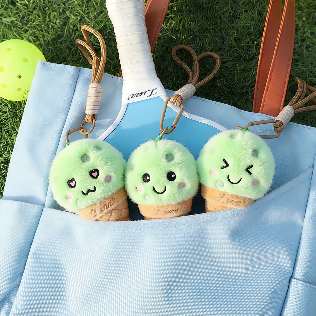 Pickleball bag on the court featuring a paddle inside and three LUZZ Ice Cream Plush Charms with different expressions