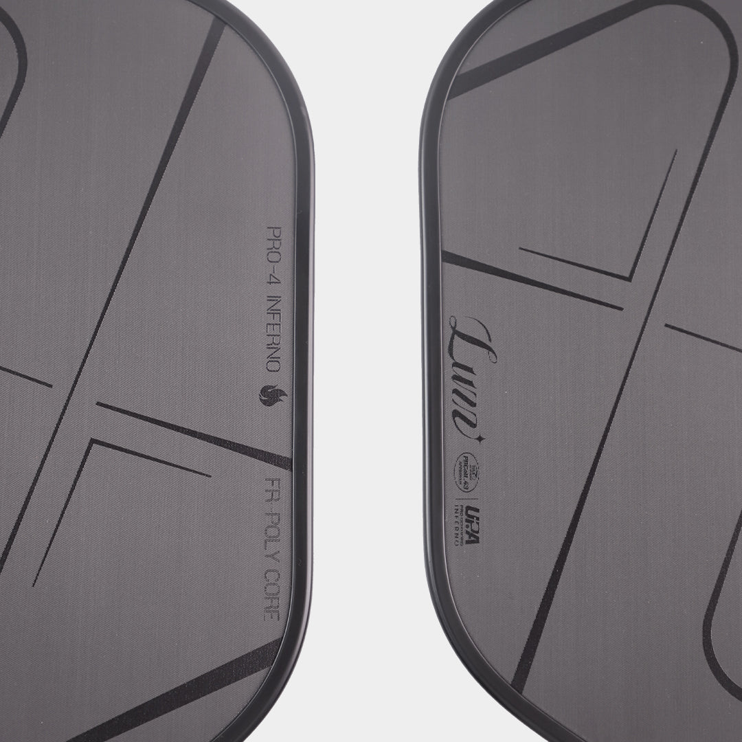 Close-up detail of the LUZZ Pro 4 Darkness Inferno paddle face featuring a 3D Grooved Carbon Fiber Weave surface, a LUZZ logo and UPA-A and USAP certification logos along the left edge, and glossy black “PRO-4 INFERNO” and “FR-POLY CORE” lettering along the right edge