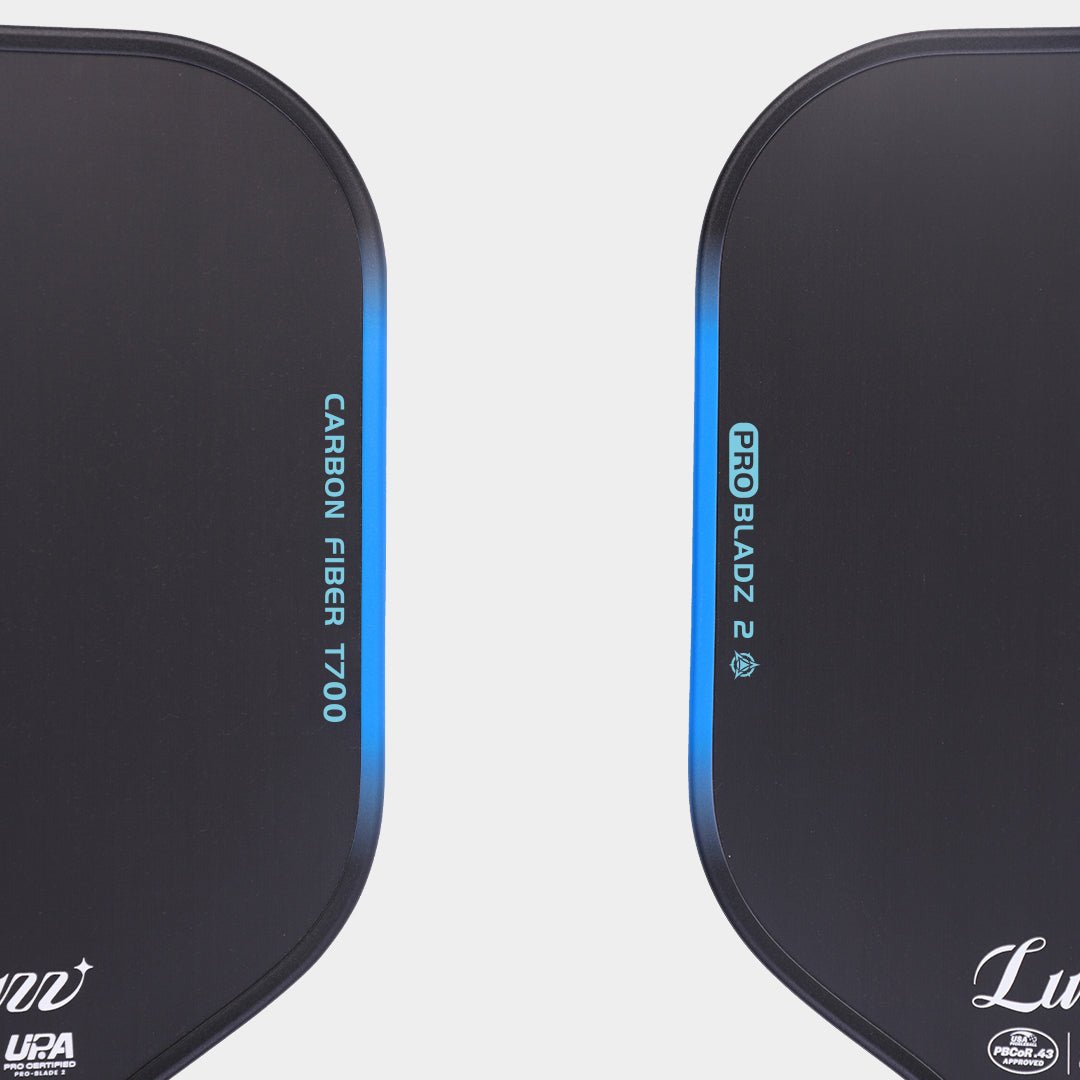 Close-up top view of two LUZZ ProBladz 2 pickleball paddles laid flat, featuring “CARBON FIBER T700” lettering on one side and “ProBladz 2” lettering on the other side of the paddle faces