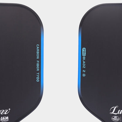 Close-up top view of two LUZZ ProBladz 2 pickleball paddles laid flat, featuring “CARBON FIBER T700” lettering on one side and “ProBladz 2” lettering on the other side of the paddle faces