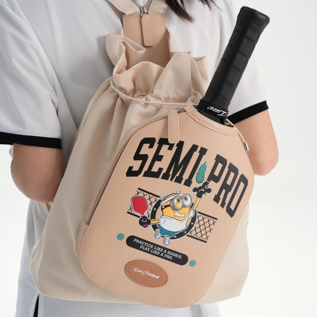 LUZZ Minions Collaboration Pickleball Backpack in beige, featuring an exterior zippered PU leather paddle compartment with a Minions graphic, a drawstring closure, and shoulder straps with a zipper for switching between single-shoulder and backpack carrying styles